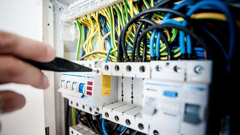 An electrician working on an open switchboard
